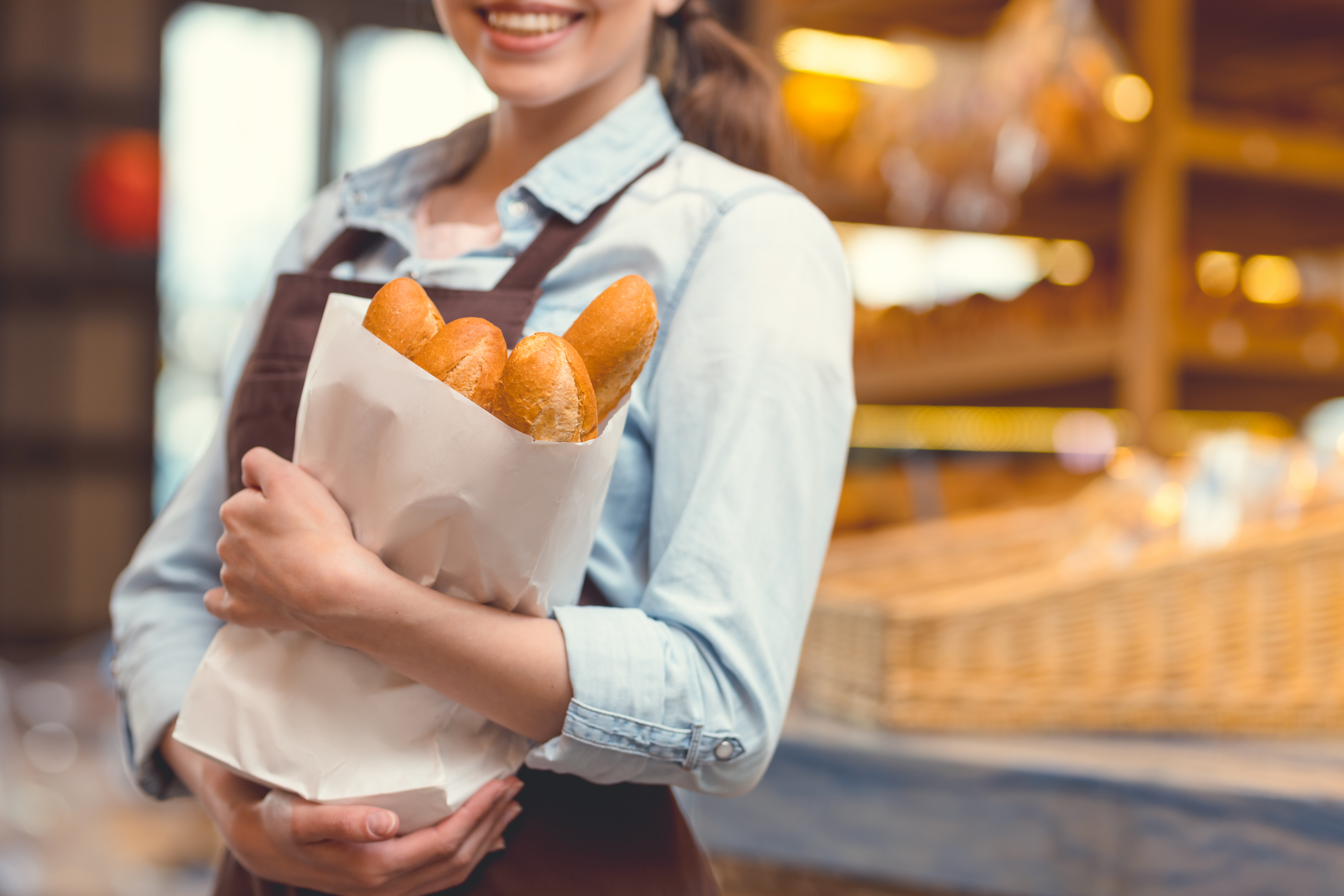 Young baker with baguettes close-up